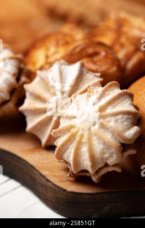 Köstliche frisch gebackene Baisons auf einem rustikalen Holztisch mit anderen Backwaren in einer warmen Küche Stockfoto