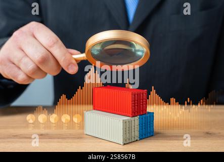 Der Geschäftsmann erkundet Container mit einer Lupe. Überwachung und Statistik. Wirtschaft und Welthandel. Analysen und Versicherung. Stockfoto