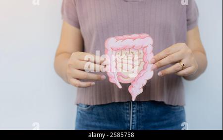 Teilbetrachtung einer Frau mit Papier aus Dickdarm auf weißem Hintergrund. Selektiver Fokus, Kopierraum. Stockfoto