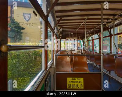 Hongkong, China - 21. Januar 2025 : die Innenausstattung Einer alten Straßenbahn mit Holzvertäfelung, braunen Sitzen und großen Fenstern bietet einen Blick auf die Straße. Th Stockfoto