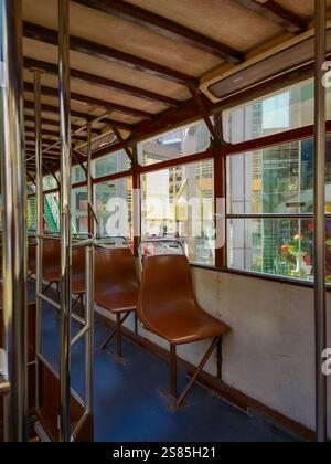 Hongkong, China - 21. Januar 2025 : Innenraum der Vintage-Straßenbahn. Braune Ledersitze, Handläufe aus Metall und große Fenster bieten einen Blick auf den Stadtrand Stockfoto