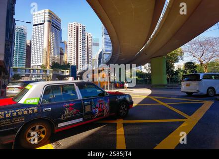 Hongkong, China - 21. Januar 2025 : an einer Kreuzung unter einer kurvenreichen Hochstraße wartet Ein Stadttaxi, darunter Wolkenkratzer Stockfoto