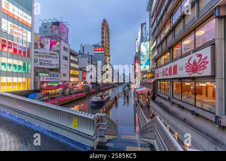 Blick auf farbenfrohe Werbung in Dotonbori, lebhaftem Vergnügungsviertel in der Nähe des Flusses in der Abenddämmerung, Osaka, Honshu, Japan Stockfoto