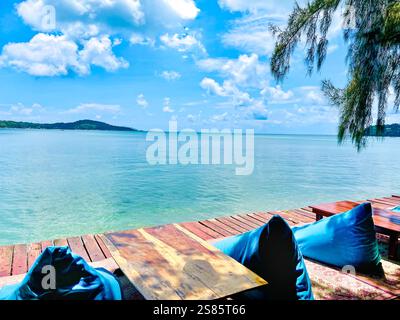 Eine ruhige und ruhige Umgebung mit einem Holztisch mit zwei weichen blauen Poufs auf beiden Seiten, die zum Entspannen einladen. Die Szene öffnet sich zu einem Awe-insp Stockfoto