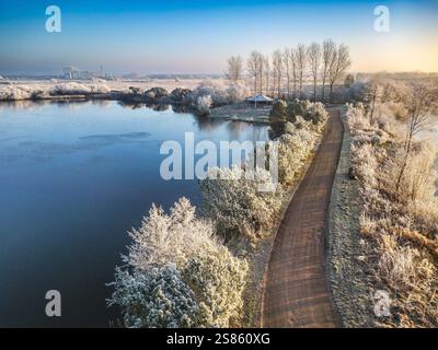 Eine wunderschöne Vogelperspektive zeigt eine frostige Winterlandschaft mit schneebedeckten Bäumen entlang einer unbefestigten Straße, umgeben von gefrorenen Seen, die Natu betont Stockfoto