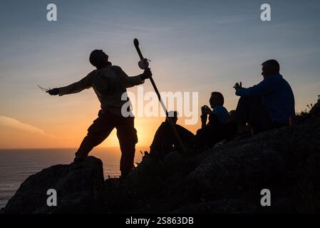 Pilger auf dem Kap Finisterre, der das Ende des Camino de Santiago in Spanien. Silhouette eines Mannes auf Felsen mit einem Spazierstock, wi Stockfoto