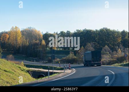 Logistik, Warenversand, Straßentransport – Lkw fährt am Herbsttag auf asphaltierter Landstraße Stockfoto