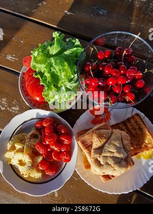 Lebendige, farbenfrohe Auswahl an frischen Speisen auf einem rustikalen Holztisch, köstliche und appetitliche Präsentation, Sommermahlzeit oder Picknick Stockfoto