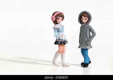 Figuren von jungen Männern und Frauen in Winterkleidung, die auf weißem Hintergrund stehen Stockfoto