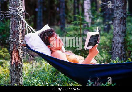 Frau mit Buch in der Hängematte Stockfoto