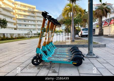 Reihe geparkter Adrigo Elektroroller (E-Scooter) in Costa Adeje. Teneriffa, Kanarische Inseln, Spanien. Januar 2025. Stockfoto