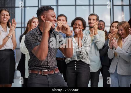 Lächelnde, multiethnische Kollegen, die alltäglichen Geschäftserfolg oder Sieg im Büro feiern. Stockfoto