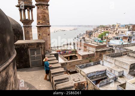 Junge Frau auf dem Dach der Moschee mit Blick auf die Altstadt von Varanasi und den Fluss Ganges in Uttar Pradesh, Indien. Stockfoto