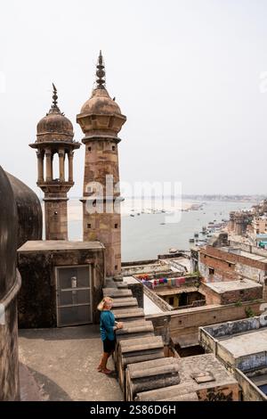 Junge Frau auf dem Dach der Moschee mit Blick auf die Altstadt von Varanasi und den Fluss Ganges in Uttar Pradesh, Indien. Stockfoto