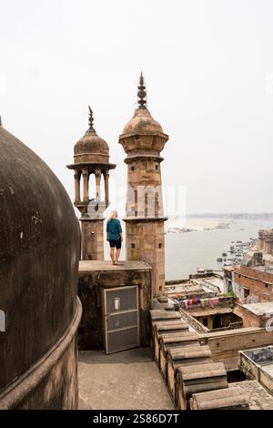 Junge Frau auf dem Dach der Moschee mit Blick auf die Altstadt von Varanasi und den Fluss Ganges in Uttar Pradesh, Indien. Stockfoto