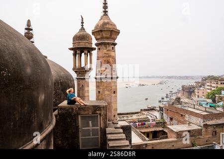Junge Frau auf dem Dach der Moschee mit Blick auf die Altstadt von Varanasi und den Fluss Ganges in Uttar Pradesh, Indien. Stockfoto