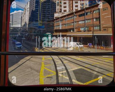 Hongkong, China - 21. Januar 2025 : Eine lebendige Straßenszene, die von einem Straßenbahnfenster aus betrachtet wird und Stadtgebäude, Fahrzeuge und Straßenbahnschienen zeigt. Die Pers Stockfoto