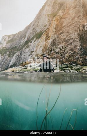 Ein Mann ist im Wasser, trägt einen Neoprenanzug und eine Maske. Er schaut in die Kamera Stockfoto
