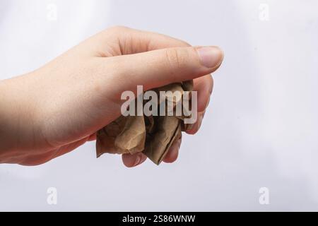 Die weibliche Hand hält eine zerknitterte Papierkugel auf weißem Hintergrund Stockfoto