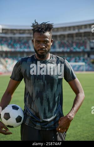Ein junger Mann steht in einem Stadion mit einem Fußball in der Hand Stockfoto