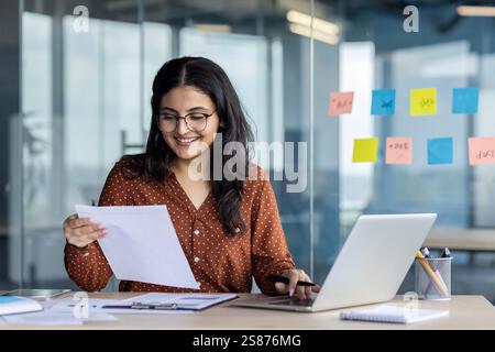 Papierkram Büroarbeit, junge erfolgreiche Latina-Frau, die mit Dokumenten und Verträgen im Büro am Arbeitsplatz arbeitet. Zufriedene Frau, die lächelnd prüft, Berichte und Steuerformulare. Stockfoto
