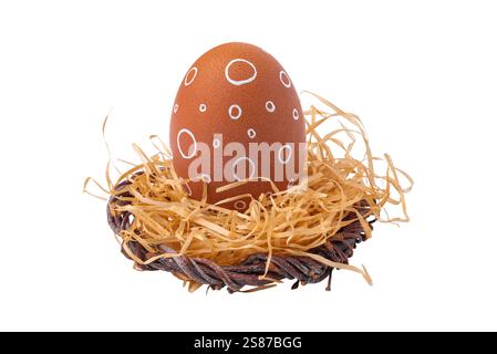 Ein Osterei mit weißem Ornament in einem Nest mit Stroh isoliert auf weißem Hintergrund Stockfoto