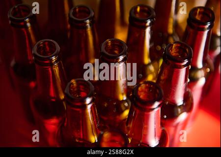 Eine Sammlung leerer Bierflaschen aus braunem Glas, aufgenommen mit dramatischer Beleuchtung, die ein Gefühl der Vollendung, des Recyclings und des Umweltbewusstseins weckt. Stockfoto