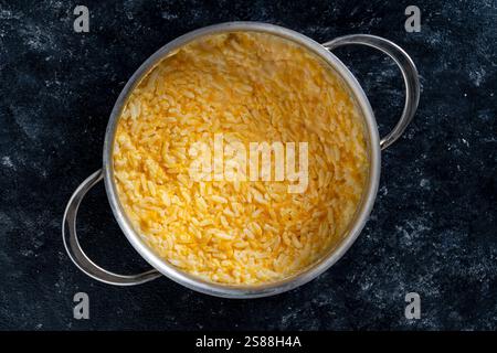 Süßer Kürbisbrei mit weißem Reis, Honig und Milch in einem Topf auf einem Tisch, Nahaufnahme, Blick von oben. Frühstück im Herbst Stockfoto