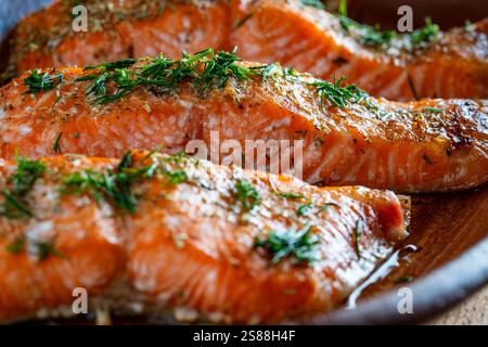 Im Ofen gebratene Lachsfilets, bestreut mit frischen grünen Kräutern und Gewürzen in einer Auflaufform, Nahaufnahme. Gesunde Ernährung Stockfoto