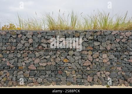 Moderne Entwicklung der Strandpark-Umwelteinrichtungen, Gabionenzaun-Wand aus Stahlgitter gefüllt mit Steinen, die die Bewegung von Dünensand einschränken Stockfoto