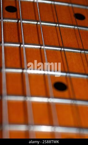 Nahaufnahme des Griffbretts einer Gitarre. Das Bild zeigt den Griffdraht und das Holz des Griffbretts. Es sind keine Personen anwesend. Das Bild ist einfach Stockfoto