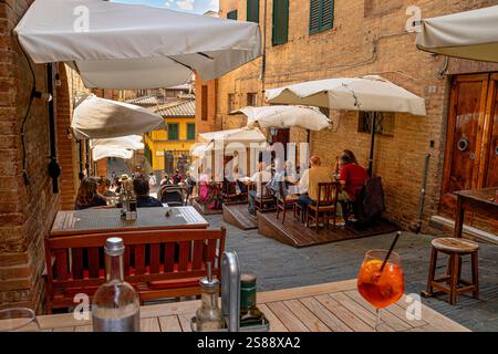 Die Leute sitzen in zwei Restaurants, die nebeneinander an der Costa Sant'Antonio liegen, einer sehr steilen, engen Straße in Siena, Italien Stockfoto