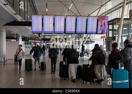 Touristen und Passagiere gehen mit ihrem Gepäck zum Flugsteig am Flughafen Schiphol in Amsterdam. Stockfoto