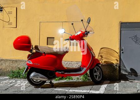 Eine rote Vespa parkte vor einem Gebäude in Siena, Italien Stockfoto