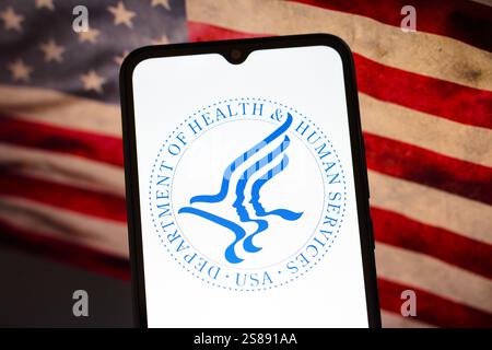 In dieser Fotoabbildung wird das Logo des United States Department of Health and Human Services (HHS) auf einem Smartphone-Bildschirm mit der amerikanischen Flagge im Hintergrund angezeigt Stockfoto