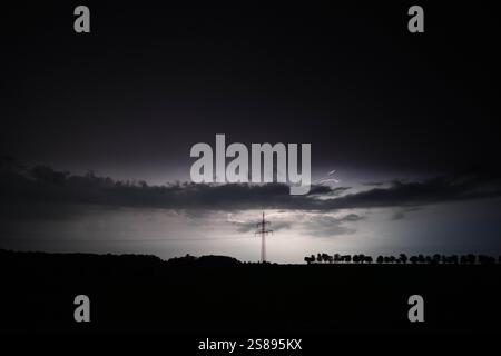Ein dunkler Himmel mit einem hohen Turm in der Mitte. Der Himmel ist bewölkt und der Turm wird von Blitzen beleuchtet Stockfoto