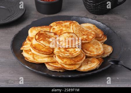 Köstlicher Stapel goldener Pfannkuchen, serviert mit Kaviar auf einem rustikalen Tisch Stockfoto