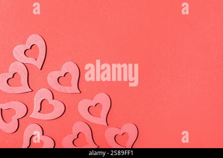 Rosafarbene Herzen mit Ausschnitten auf einem leuchtend roten Hintergrund schaffen ein romantisches und festliches Design mit Kopierraum zum Valentinstag. Draufsicht, f Stockfoto