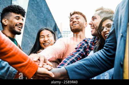 Eine Gruppe von Leuten, die Hände stapeln und gemeinsam feiern. Verschiedene Freunde, die Spaß haben, einander zu unterstützen Stockfoto