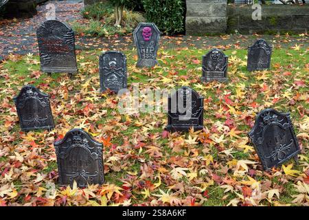 Halloween-Grabsteine-Dekoration im Freien umgeben von herabfallenden Herbstblättern Stockfoto