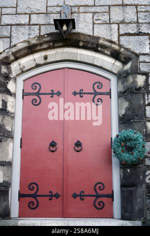 Weihnachtskranzdekoration und rote Holztür einer Kirche Stockfoto