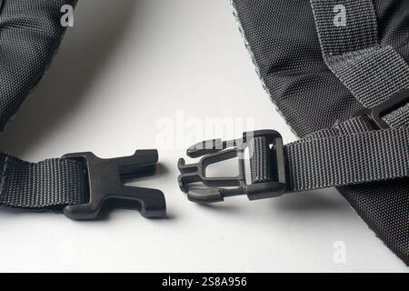 Nahaufnahme der abgetrennten schwarzen Kunststoffschnalle mit Schnellverschluss am Schultergurt des Rucksacks auf weißem Hintergrund Stockfoto