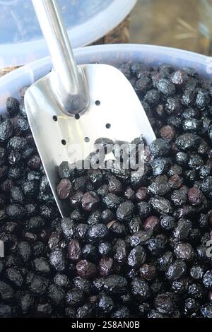 Schneidet schwarze Oliven mit einem Löffel in einer Schüssel, Stockfoto