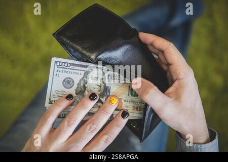 Ein Geschäftsmann nimmt am Zahltag Geld aus einer schwarzen Brieftasche. Ein Mann mit bemalten Nägeln zählt Geld in seiner Brieftasche. Stockfoto