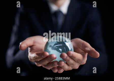 Geschäftsmann hält Glaskugel mit Kontinenten in Händen Stockfoto