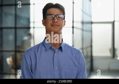 Nahaufnahme eines lächelnden asiatischen Geschäftsmanns, der in einem modernen Büro steht Stockfoto