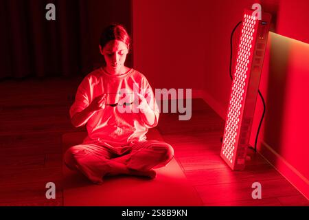 Eine junge Frau, die sich auf die Rotlichttherapie vorbereitet, indem sie Schutzbrillen in Innenräumen hält Stockfoto