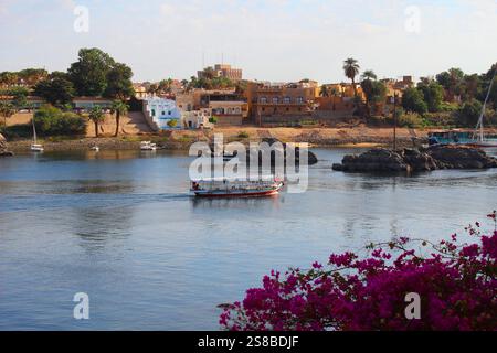 Kleines Segelboot, das den nil in Assuan in Ägypten überquert, umgeben von Felsen und Pflanzen Stockfoto