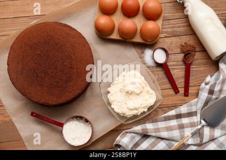 Köstlicher Schokoladen-Biskuitkuchen mit Zutaten auf hölzernem Hintergrund Stockfoto