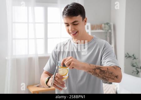 Sportlicher junger Mann mit einer Flasche Zitronenwasser zu Hause Stockfoto